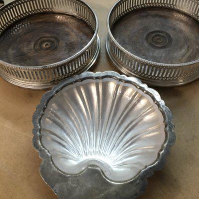 A pair of wine coasters and a silver butter dish .