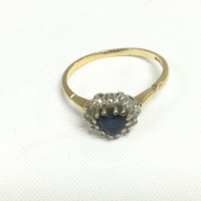 An 18ct gold heart shaped ring set with a central sapphire surrounded by diamonds, approx 3.2g and approx size R. Shipping category A.