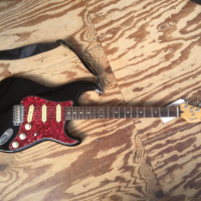 A Fender Squier Stratocaster in black with a red tortoiseshell pickguard. No case.