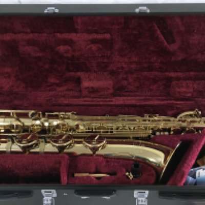 A cased Yamaha baritone saxophone with accessories and stand.