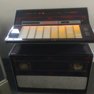 A Rock Ola 460 jukebox. Powers up and turntable spins but speaker cones are damaged. No sound. In need of restoration.