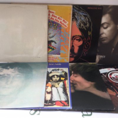 Two bags containing sixteen Beatles and related LPs and 12" singles including a side loading numbered White Album (no portraits), a US Capitol issued Magical Mystery Tour, Mind Games and others. Plus a Beatles book.