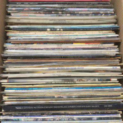 A box of LPs and 12" singles by various artists including David Bowie, Elton John, Prince Buster and others.