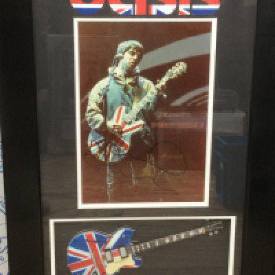 A framed and glazed Oasis display signed by Noel Gallagher, approx 68cm x 43cm.