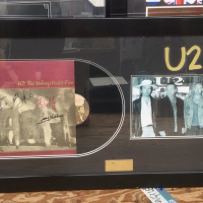 A framed and glazed U2 display signed by all band members with COA, approx 55cm x 100cm.