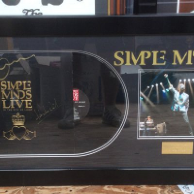 A framed and glazed Simple Minds display signed by Jim Kerr, Charlie Burchill and Mick MacNeil, approx 50.5cm x 91cm.