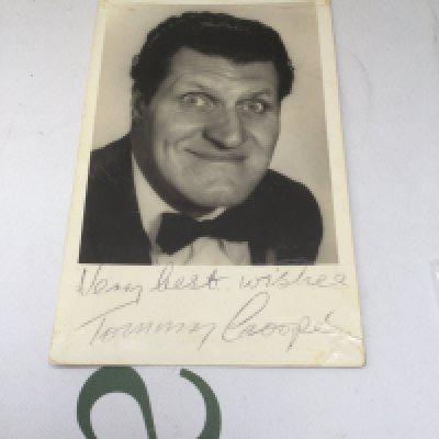 A signed Tommy Cooper photographic card with handwritten notes on the reverse.