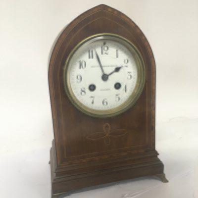 An Edwardian inlaid mahogany mantel clock with an enamel dial and brass French movement striking on a gong. With pendulum. 27cm high.