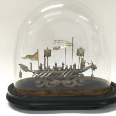 A Chinese silver boat under a glass dome. 9cm tall 15cm wide. Dome 17cm tall. This lot cannot be posted