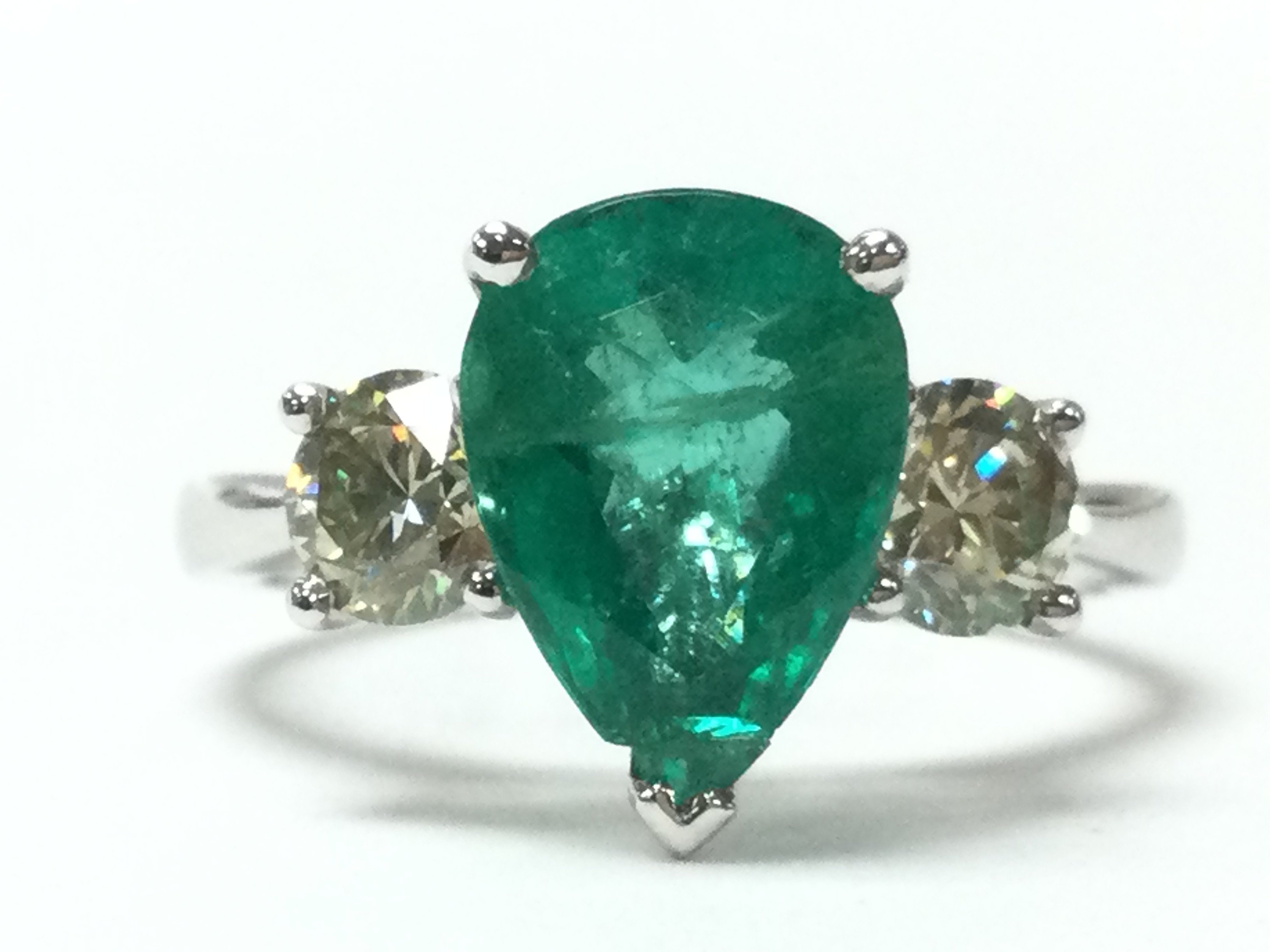 18ct white gold three stone ring. Pear single emerald flanked by 2x diamonds. Emerald 2.17ct. Diamonds 0.81ct. Size M/N. 3.9g. Postage category A