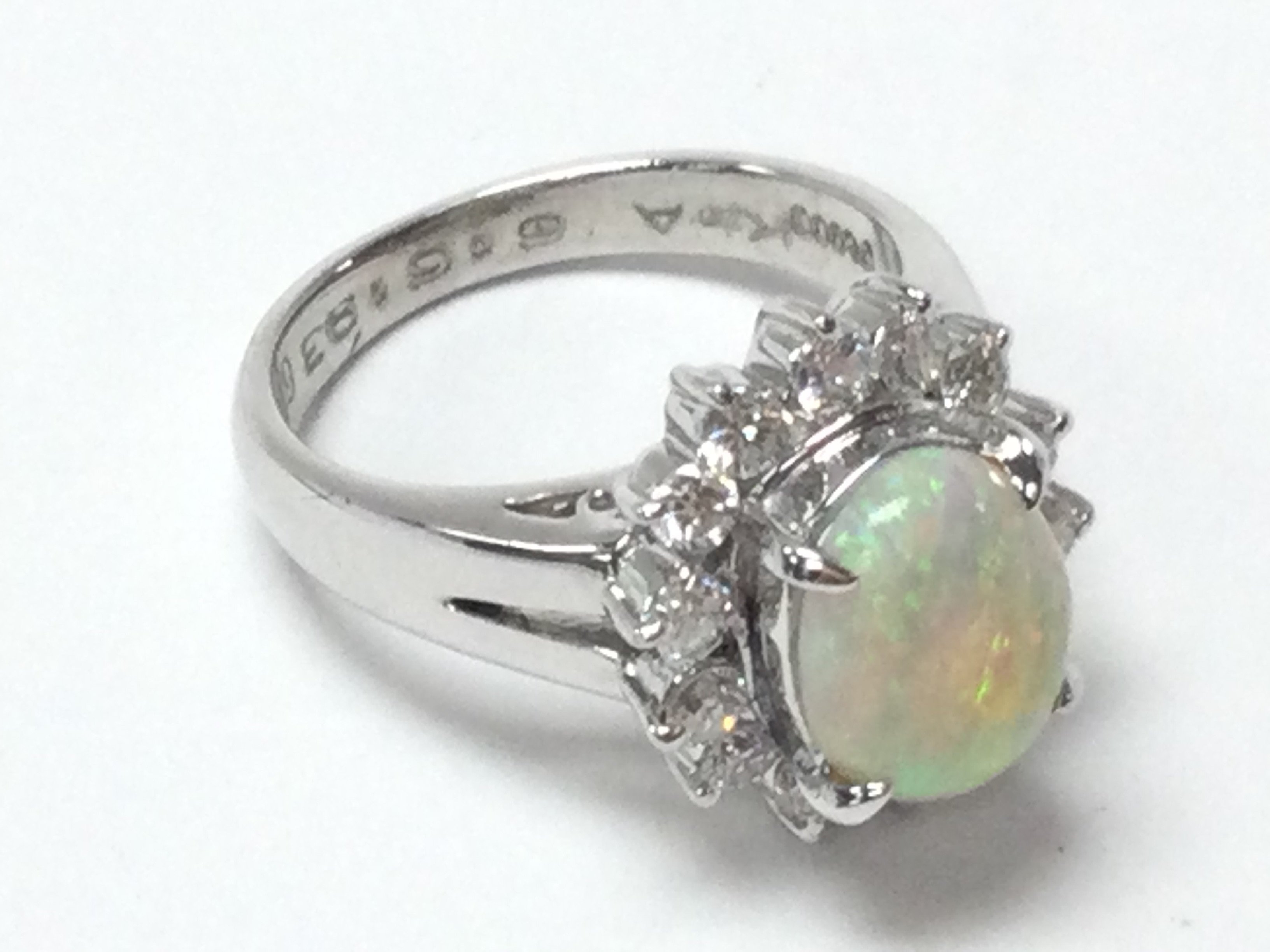 A platinum ring set with a Cabochon oval opal and a halo of RBC diamonds. Opal 1.05ct Approximately. Diamonds 0.49 approx. Size H Postage category A