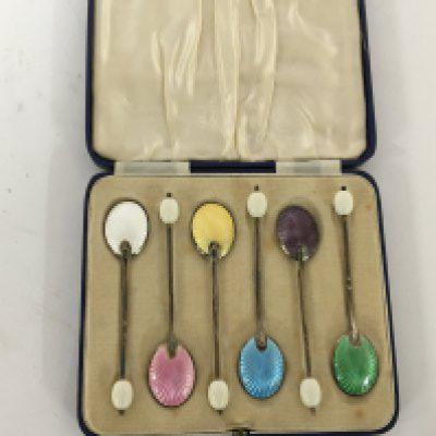 A cased set of silver and enamel coffee spoons.