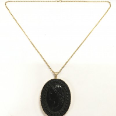 A Victorian jet oval pendant set in a 9ct gold frame on a 9ct gold chain. Postage B