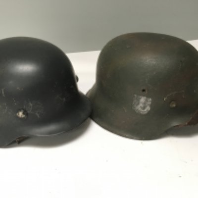 A German Third Reich helmet M42 pattern the side with faded SS decal and one other steel combat helmet possible Spanish both with liners and with soldiers personnel name inscription (2)