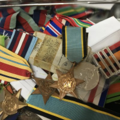 A tin containing II world war medals and retrospective copy II world war campaign stars ribbons and other medals a mixed lot.