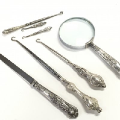 A collection of silver items to include silver handled magnifying glasses and button hooks. This lot cannot be posted