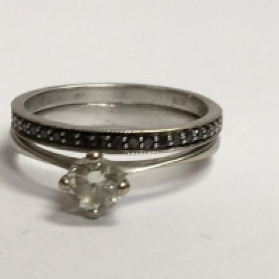 A 18 ct white gold ring with central diamond surround by black diamond chips . Size k .