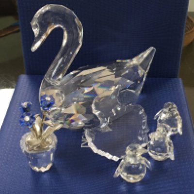 A Swarovski boxed swan, three miniature baby birds with slightly larger bird shaped base, together with a miniature Swarovski flower group
