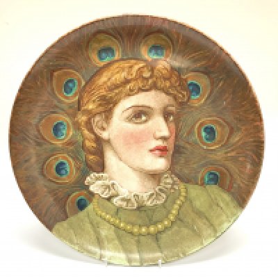 A large earthenware pottery charger with hand painted view of a lady using peacock feathers. Named and dated to reverse 1884 Ellen Slaughter. 36.5cm (D)