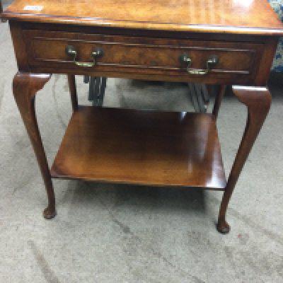 A walnut side table with single drawer on cabriole legs .