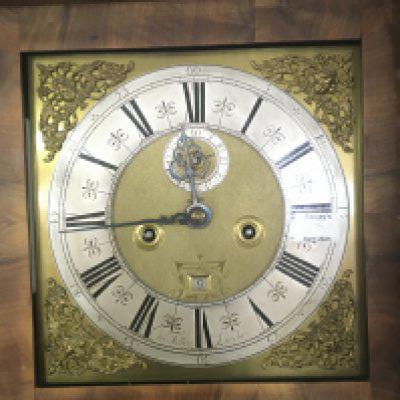 An Early 18th century figured walnut long case clock with a brass dial and silvered chapter ring maker Cha Tolley London. With date aperture and second subsidiary dial. Eight day going with pendulum and weights the case hood with barley twist pillars with a circular glass panel to the door. The clock restored and in appearing in good condition height 215cm