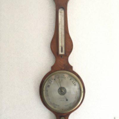 A George lV mahogany and boxwood banjo barometer with a silvered dial and thermometer box.