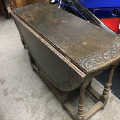 An oak 18th century style drop leaf table with a carved design , single drawer and turned legs . 111cm long 94cm wide 70cm tall.