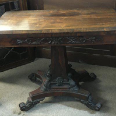 An early William IV rosewood tea table the hinged top above a frieze with applied mouldings the shaped column base with corner scrolls and conforming scroll feet.