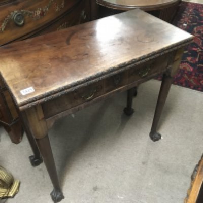 A George III mahogany tea table with a twin flap top above single drawer on tapering legs and ball and claw feet.