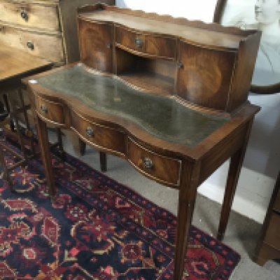 A Mahogany Carlton house type desk with a raised back fitted with drawers above a tooled leather top and three further drawers on square tapering legs.