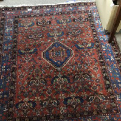 A small early 20th century hand Knotted rug with a floral pattern on a red field 132x136cm