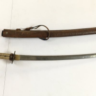 A WW2 Issue Japanese Katana with a ray skin wrapped handle and a leather scabbard, in need of restoration. Pin missing. Blade 66cm long, handle approximately 24cm long. Total length 90cm