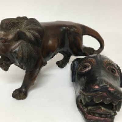 A carved hardwood sculpture of a lion length 40cm and a tribal art painted wood dog mask. (2)