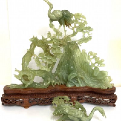 A carved Jadeite group figure depicting cranes in a mountain landscape. (A/F) 26.5cm x 29cm.