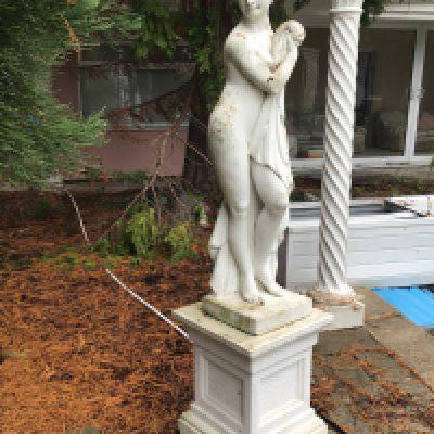 A composition Classical Garden ornament sculpture of a naked maiden on a square plinth. Height 190cm Sold in situ buyer to collect.