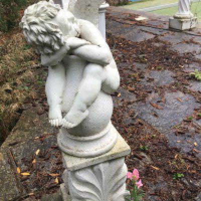 a concrete composition garden ornament of Classical influences a cherub sleeping on a shaped base good condition height 97cm. Sold in Situ buyer to collect.
