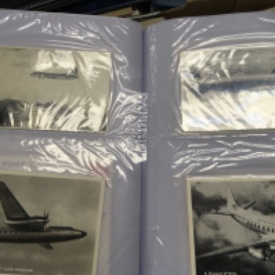 A box containing postcards including an album of Aviation postcards mainly commercial airlines 1960-70 an album of II world war cards and retrospective photos and many other postcards.