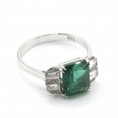An 18ct white gold ring set with a step-cut emerald flanked by RBC and baguette cut diamonds. Emerald 2.21Ct diamonds 0.26ct (RBC 0.07ct/ bag 0.19ct). Ring size M. Weight 3.3g. Postage category A