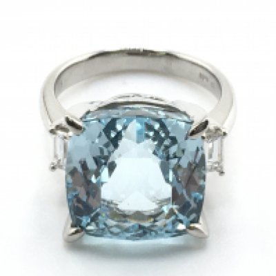 A Platinum ring set with a large square cushion aquamarine and two flanking baguette diamonds. Aquamarine 11.38ct. Diamonds 0.45ct. Ring weight 10g. Size M. Postage category A