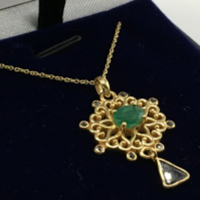 A Floral pendant in a yellow metal set with oval emerald round diamonds and a slice-cut diamond. Diamonds 0.30ct approx. Emerald 0.60ct approx