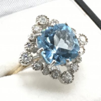 A 9ct white and yellow gold vintage style ring set with a large cushion cut blue topaz and RBC diamonds. Blue topaz 3.00ct, diamonds 0.60ct. Size N, total weight 5.2g. Postage category A