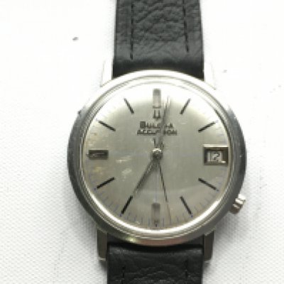 A Bulova gents watch with date aperture. Silver coloured dial and black leather strap. Seen running. Postage B