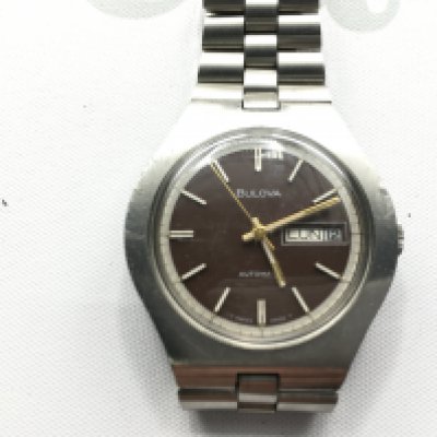 A Bulova Automatic day date wrist watch with stainless steel strap. Seen running.