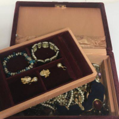 A box containing costume jewellery in a red velvet jewellery box.