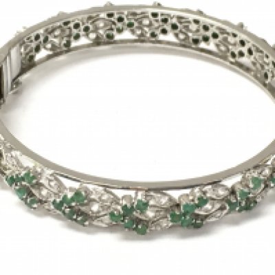 A diamond and emerald white metal bangle. Postage category a