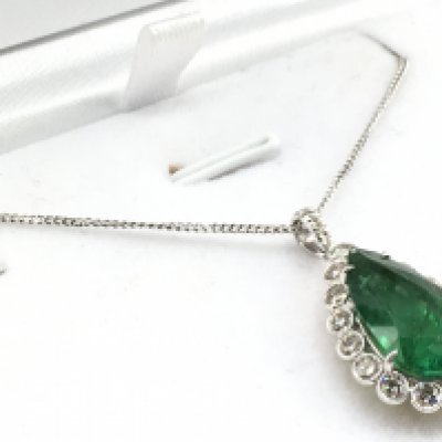 An 18ct yellow and white gold pendant set with a pear shaped emerald surrounded by RBC diamonds in a scalloped mount, with diamond bale, with silver chain, Emerald 5.48ct. Diamonds 0.97ct. Total weight 5g. Postage category A