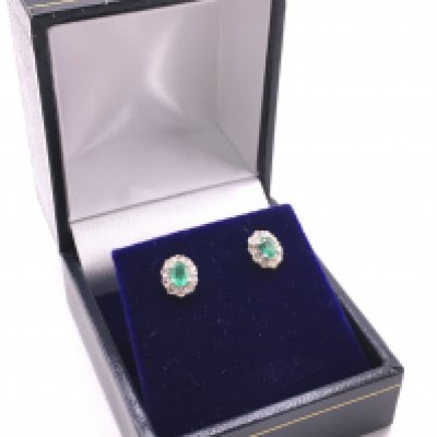 A pair of 18ct white gold oval emerald and RBC diamond cluster studs, with silicon- capped butterflies. Emeralds 0.36ct, diamonds 0.30ct. Total weight 1g. Postage category a