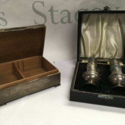 A silver cigarette box with a pair of silver salt and pepper shakers.