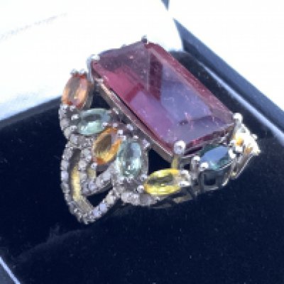 Large silver dress ring set with step cut tourmaline, surrounded by multi coloured sapphires and diamonds, boxed. Tourmaline 7.50ct. Sapphires 2.98ct. Diamonds 0.53ct. Postage category A.
