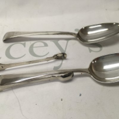 Two silver table spoons and a pair of sugar tongs .